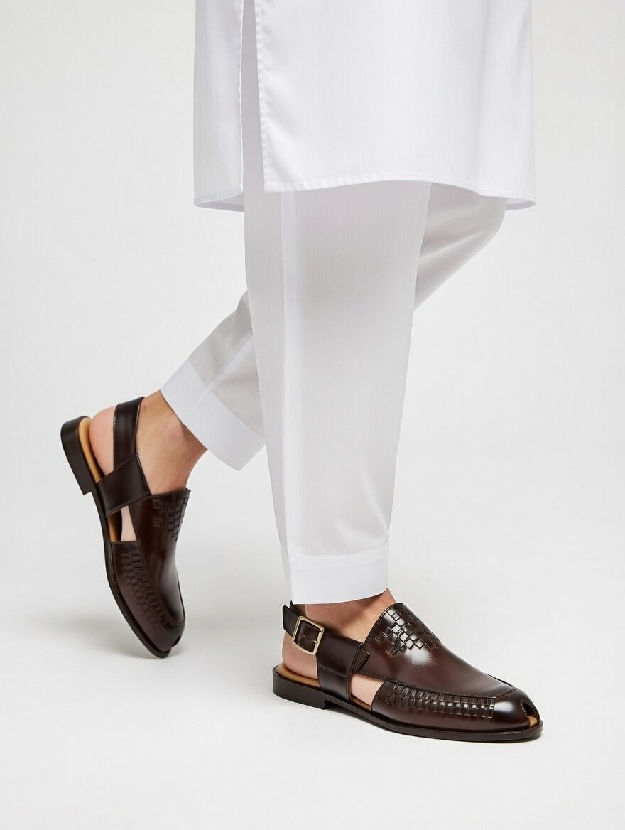 Brown leather shoes worn with white pants on a light gray background