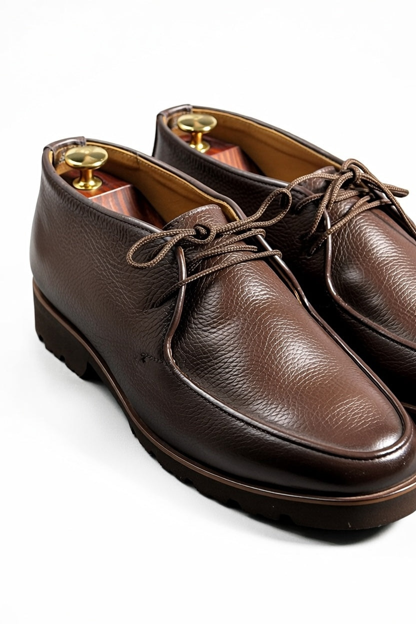 Men’s dark brown leather chukka shoes with lace-up design on white background