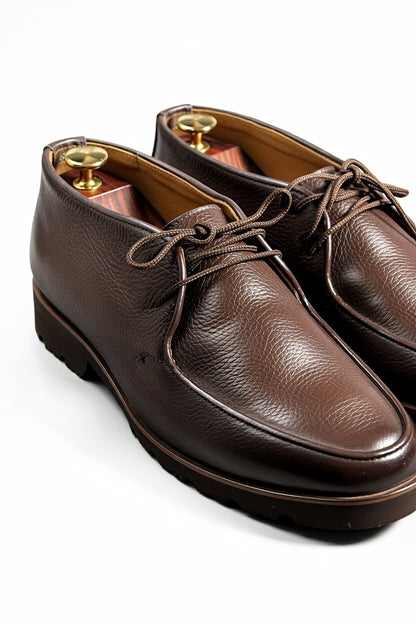 Men’s dark brown leather chukka shoes with lace-up design on white background