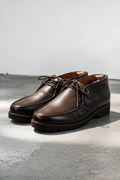 Men’s dark brown leather chukka shoes with lace-up design on white background