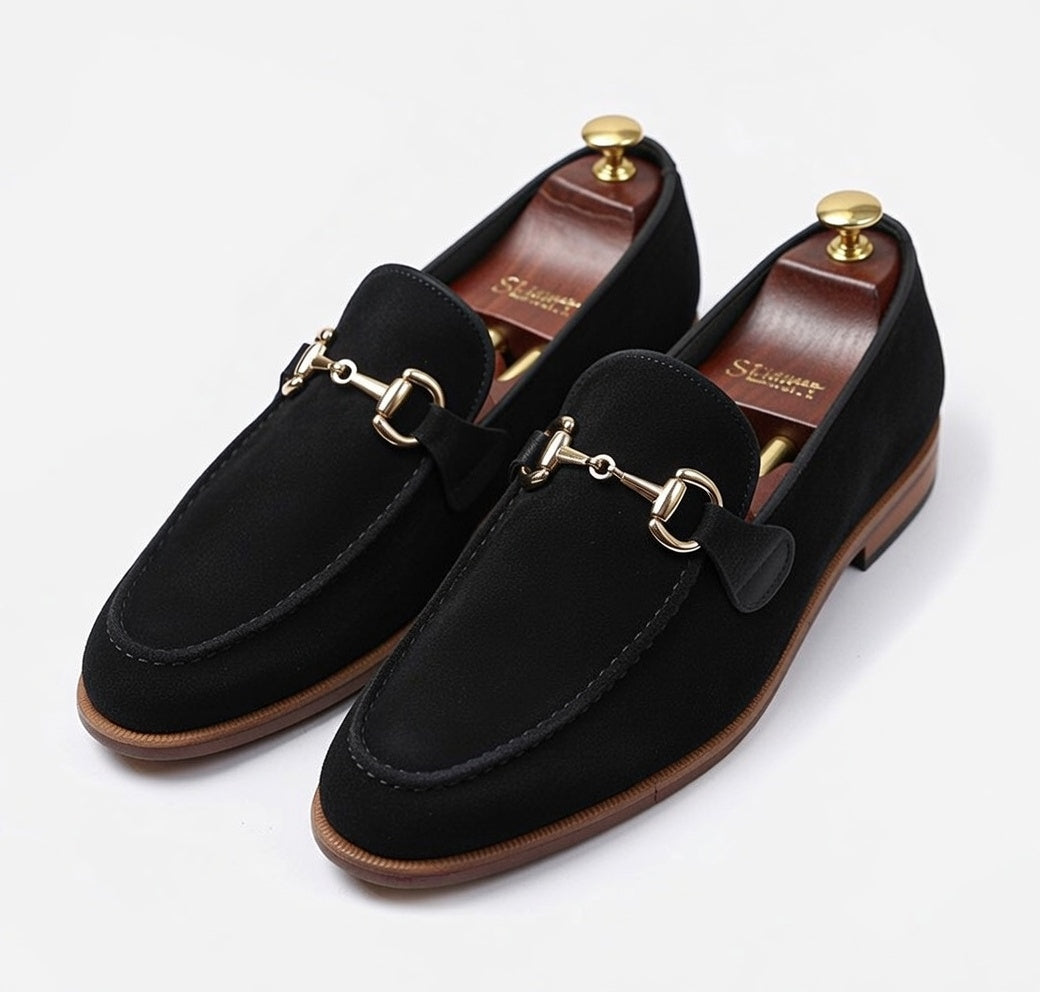 Men’s black leather horsebit loafers with gold buckle on white background