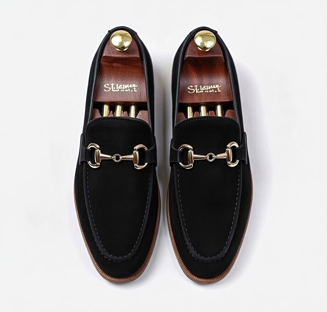 Men’s black leather horsebit loafers with gold buckle on white background