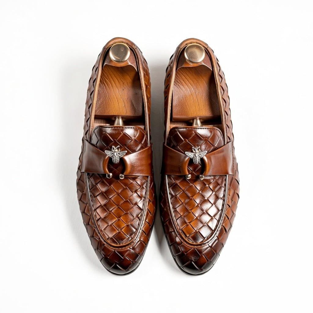 Pair of brown woven loafers with bee emblem on a white background