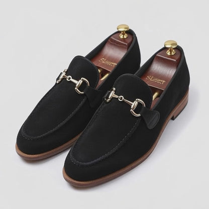 Men’s black leather horsebit loafers with gold buckle on white background