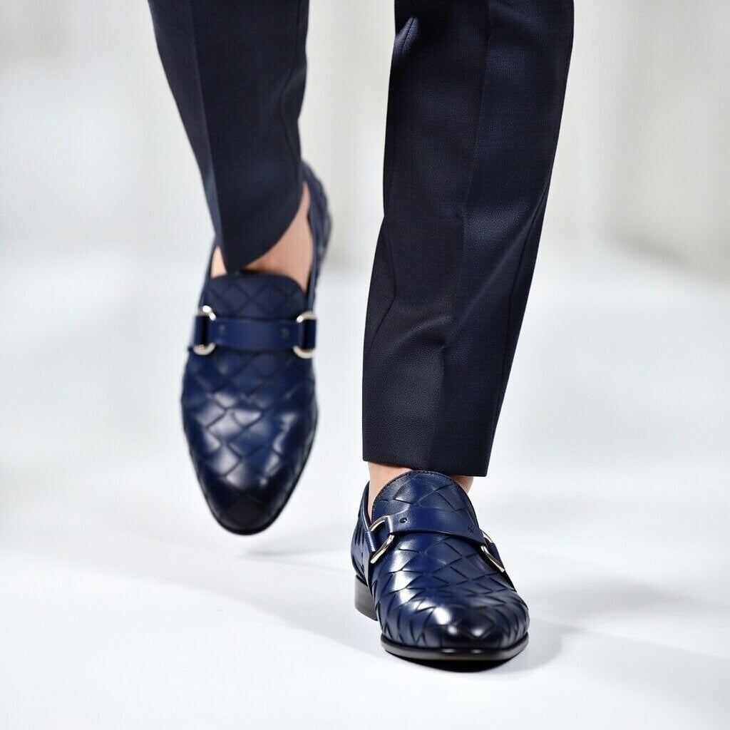 Navy blue loafers worn with dark pants on a white background