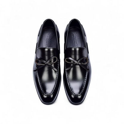 Pair of black dress shoes with brown laces on a white background