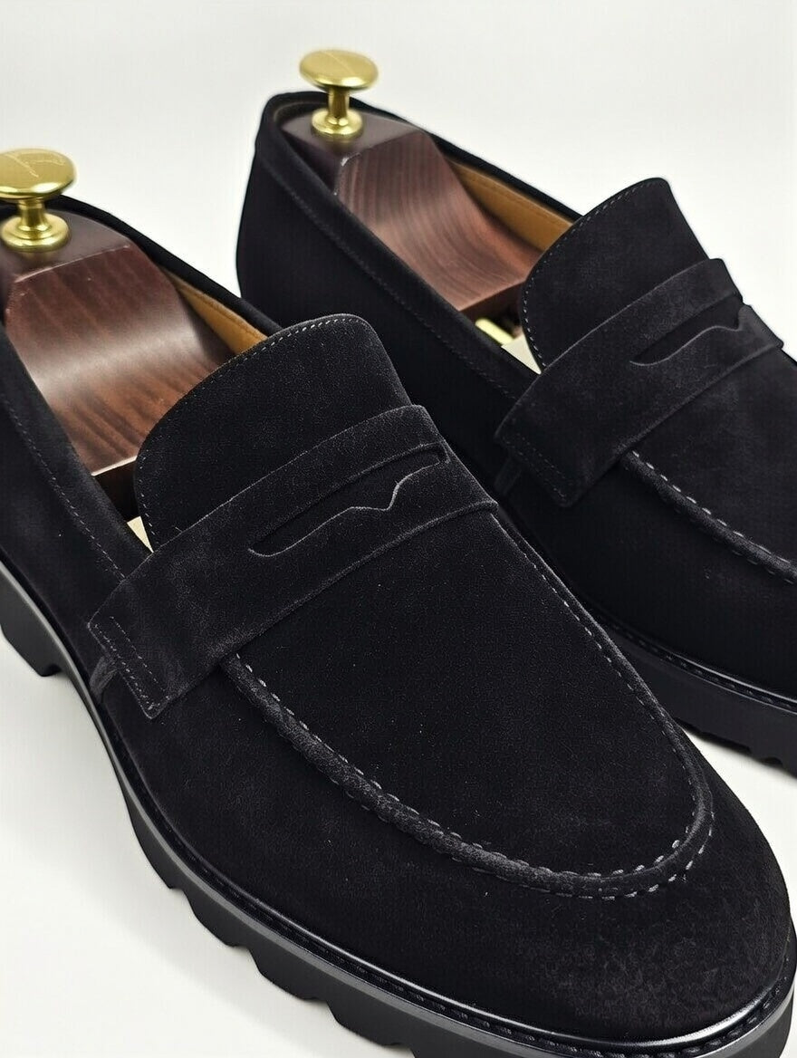 Black suede loafers with gold buttons on a white background