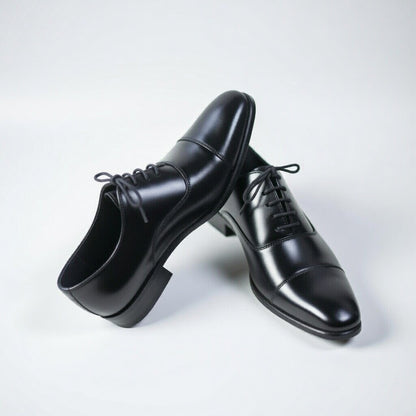 Pair of black dress shoes on a light gray background