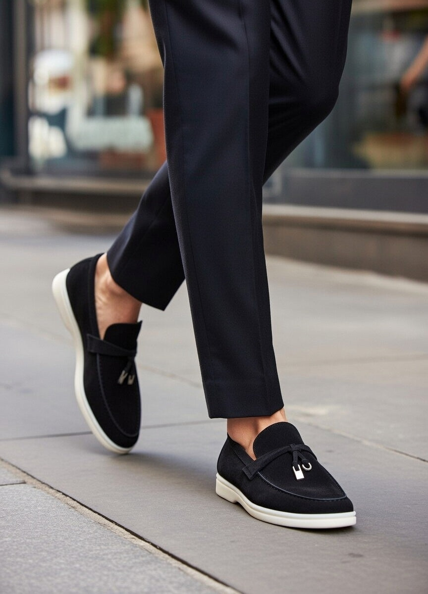 Person wearing black loafers and dark pants on a sidewalk.