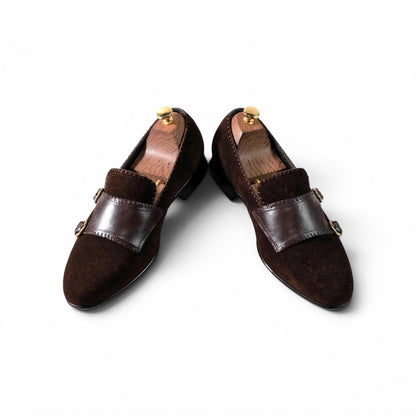 A pair of dark brown suede and leather loafers displayed on wooden shoe trees against a clean white background.