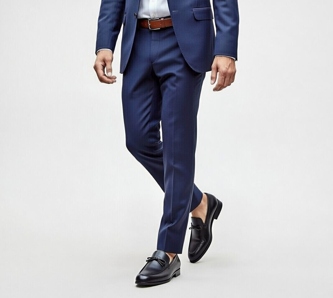 Person wearing a blue suit with black shoes on a light gray background