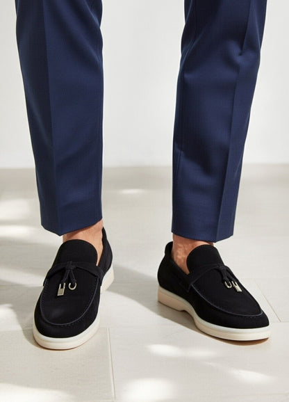 Black loafers worn with navy pants on a white background