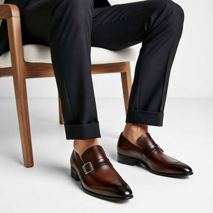 Brown dress shoes worn with black pants on a light background