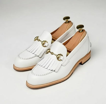 White loafers with gold accents on a light gray background