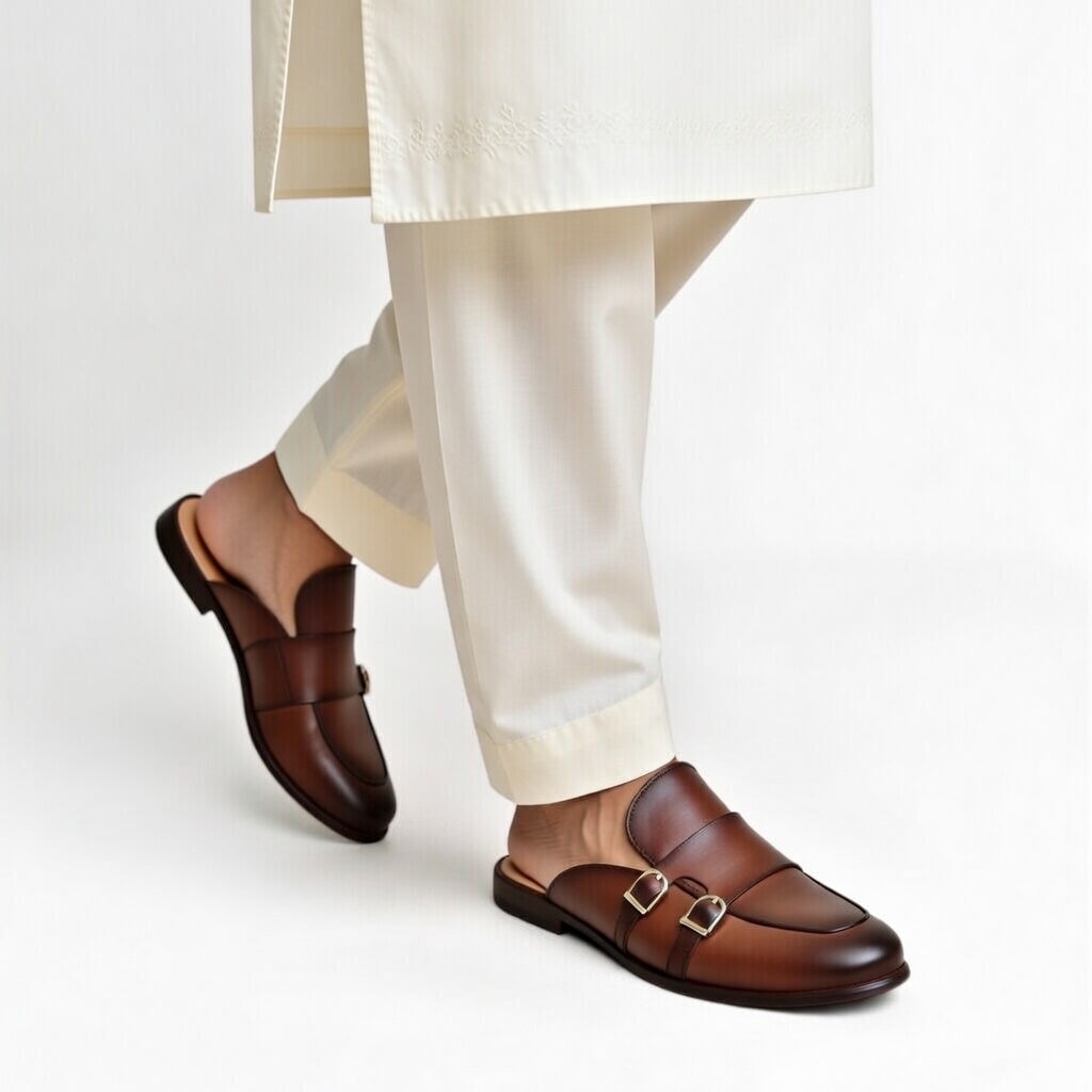 Brown loafers worn with white pants on a light gray background