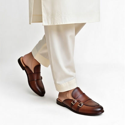 Brown loafers worn with white pants on a light gray background