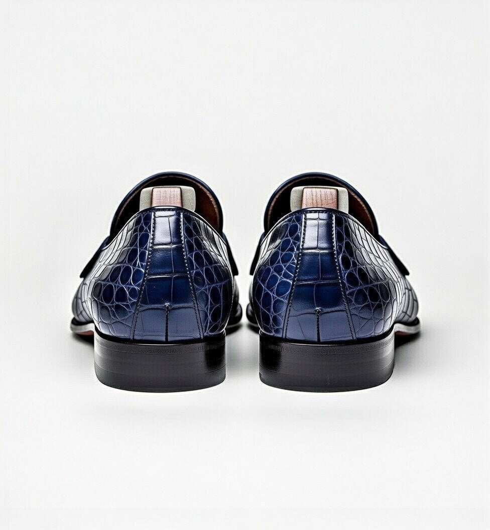 Pair of navy blue crocodile-patterned loafers on a white background