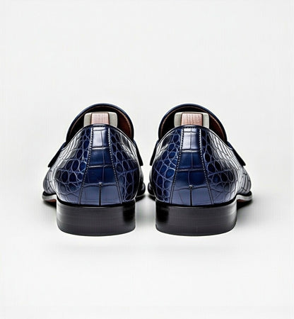 Pair of navy blue crocodile-patterned loafers on a white background