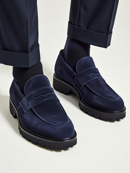 Navy blue loafers worn with navy pants on a light background
