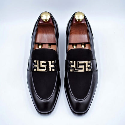 Black loafers with gold accents on a white background