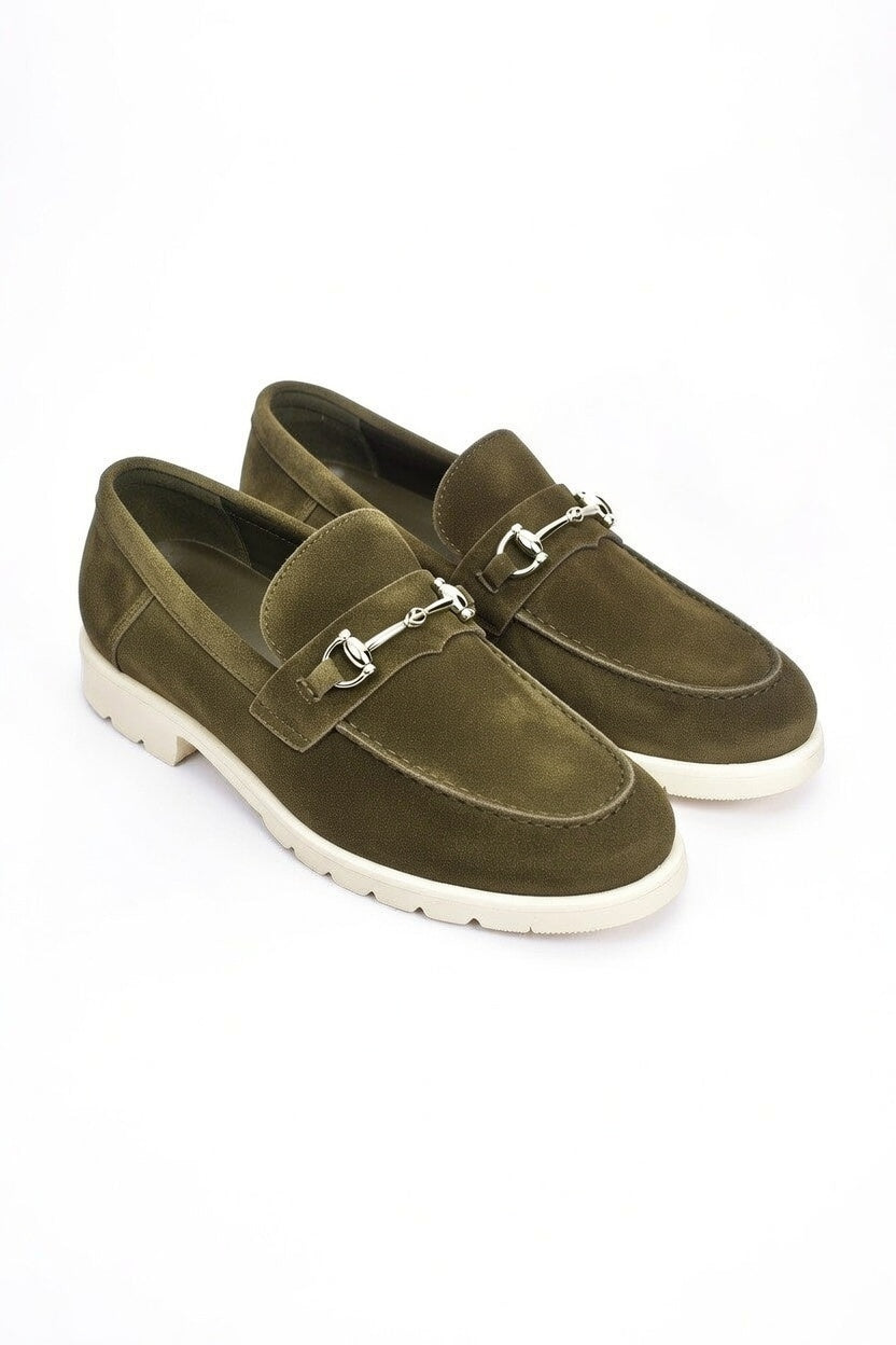 Pair of green loafers with metal buckles on a white background