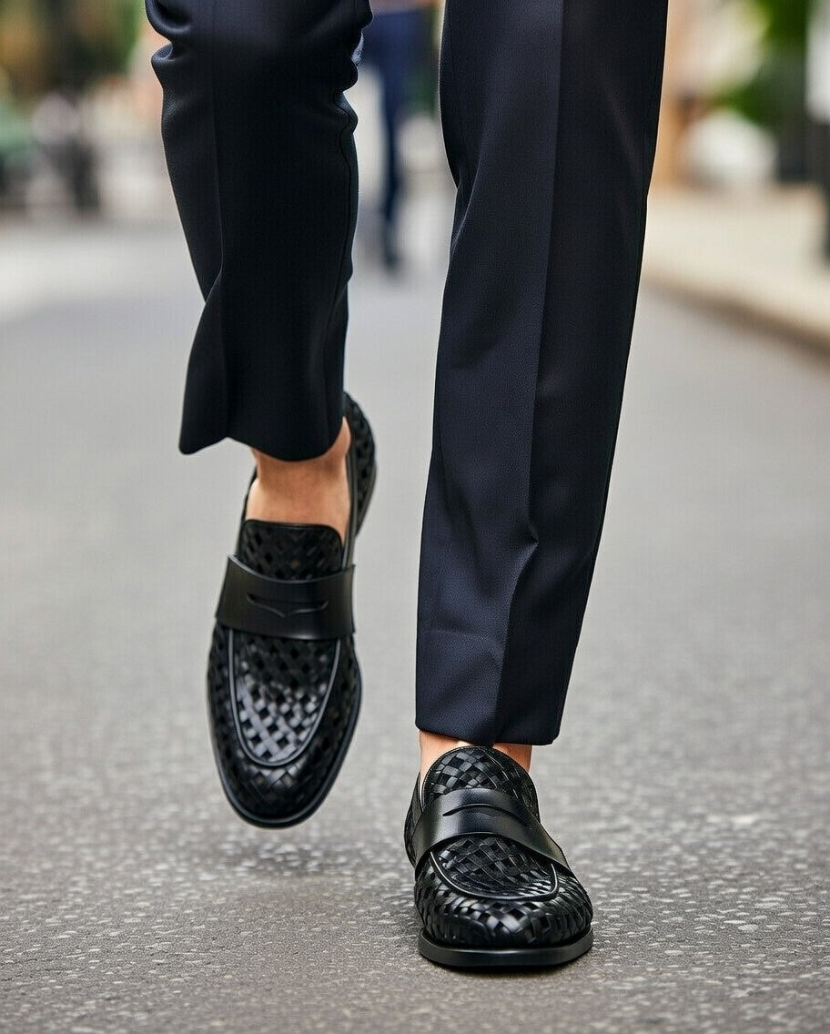 Black loafers worn with black pants on a blurred street background