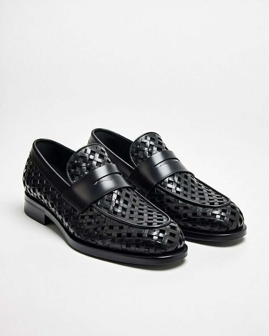 Black perforated loafers on a light gray background