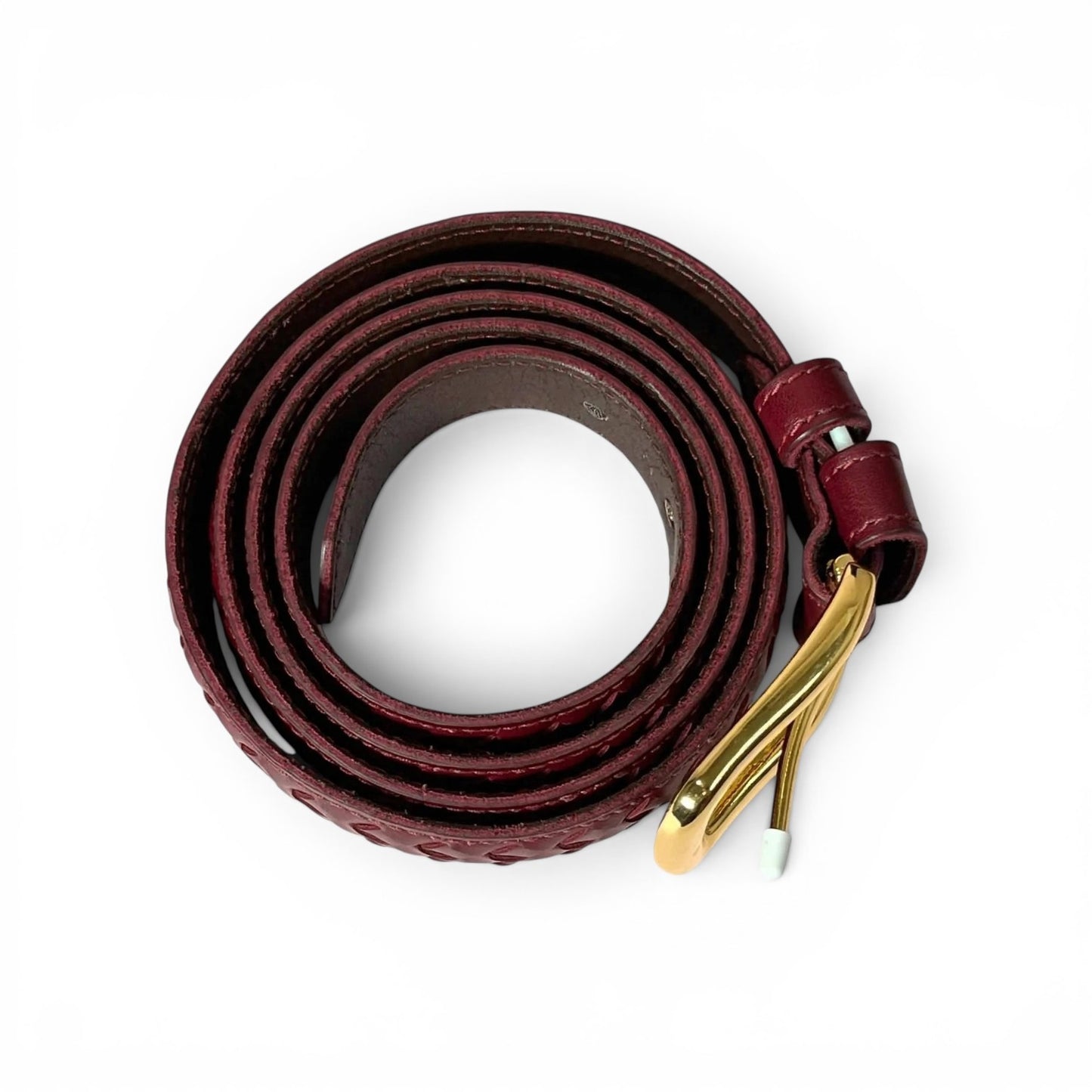 A dark burgundy leather belt coiled on a white background, featuring a textured pattern and a polished gold-tone metal buckle.