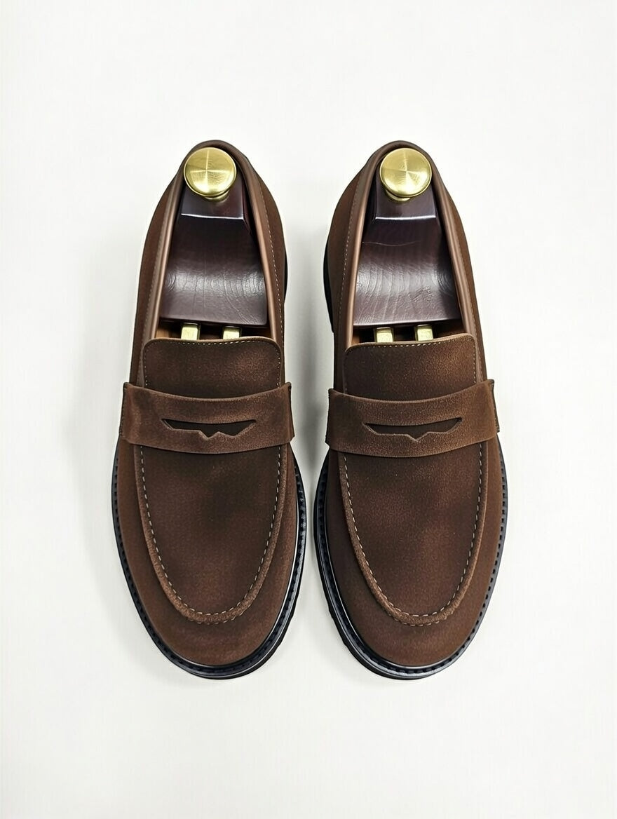 Pair of brown loafers with gold accents on a white background