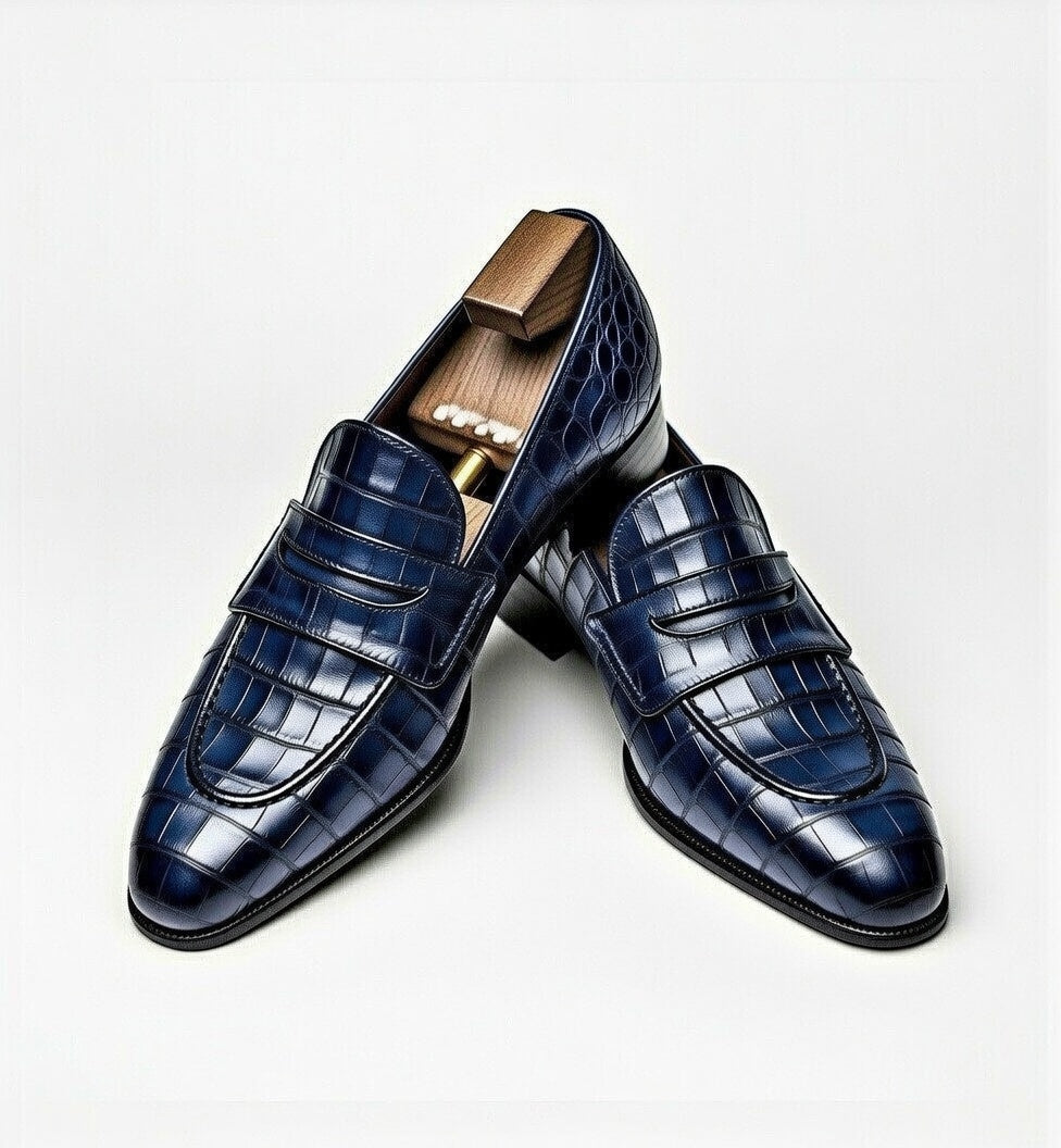 Pair of navy blue crocodile-patterned dress shoes on a light gray background