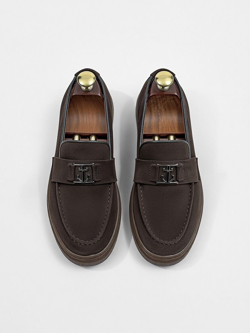 Pair of brown loafers with gold accents on a light gray background