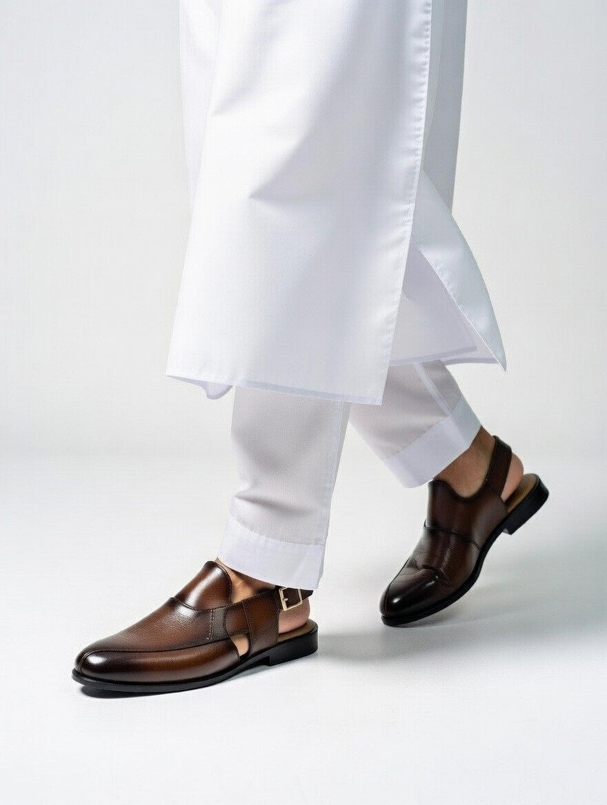 Brown dress shoes worn with white pants on a light gray background