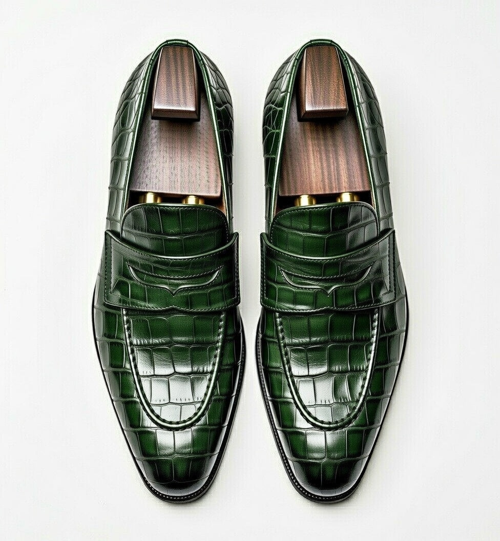 Green crocodile-patterned loafers on a white background