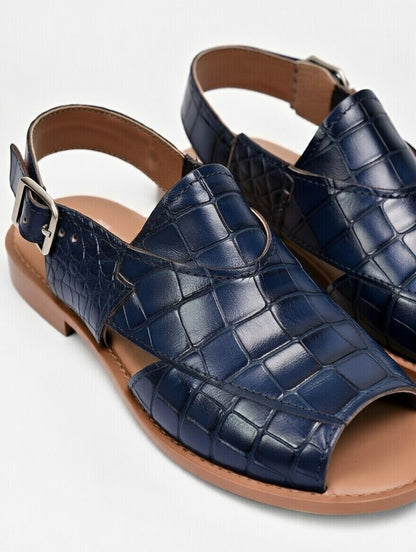 Navy blue crocodile-patterned sandals with brown soles on a light gray background