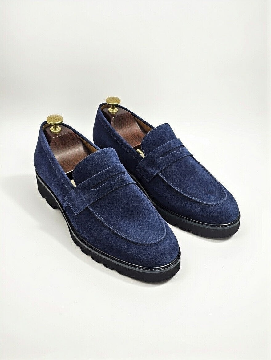Pair of blue suede loafers on a white background