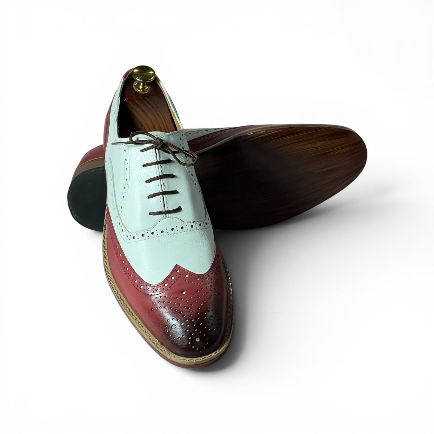 A pair of men's wingtip oxford shoes with a color-blocked design featuring a pale mint green upper, a deep burgundy wingtip toe, and a dark brown wood-grain sole, displayed on a white background.