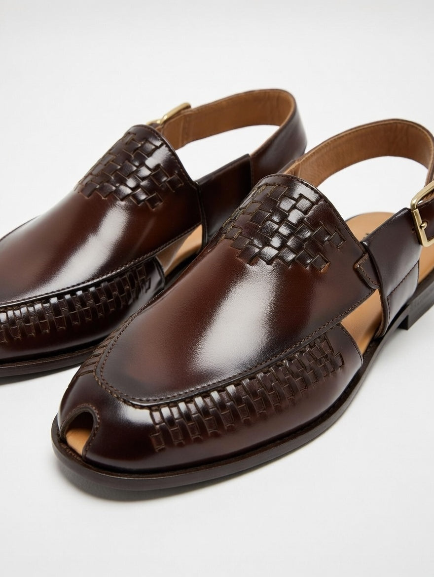 Pair of brown leather sandals with woven detailing on a light gray background