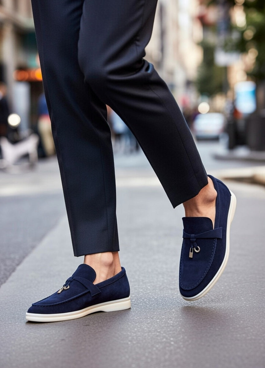 Navy loafers worn with dark pants on a city street.