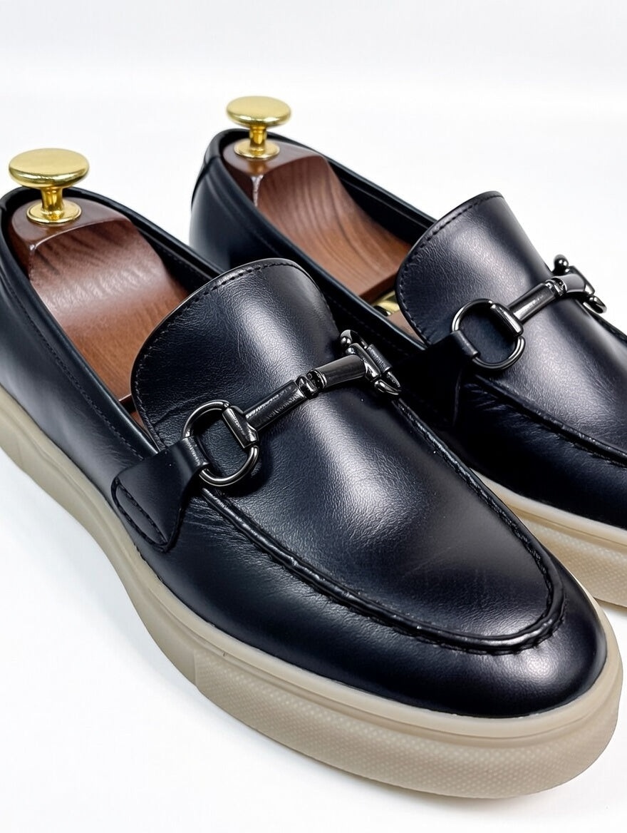 Black leather loafers with gold buckles on a white background