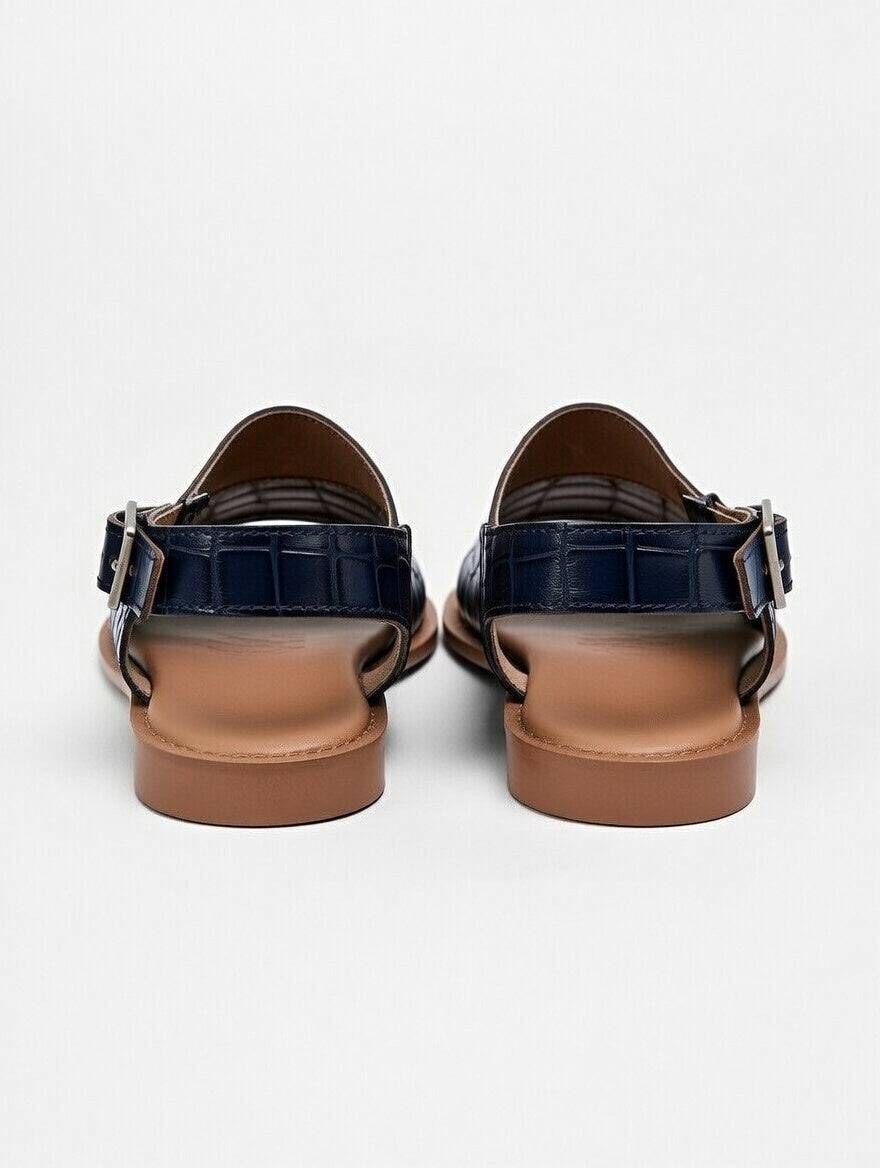 Pair of black sandals with brown soles on a white background