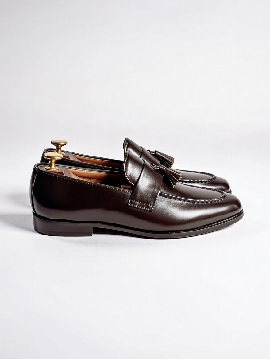 Brown loafers with a bow on a light gray background