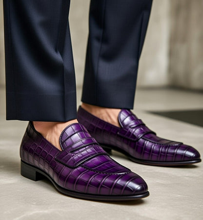 Purple loafers worn with navy pants on a neutral background