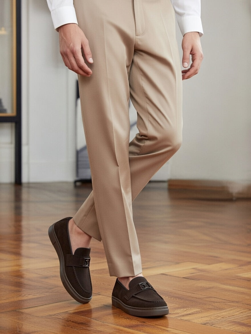 Person wearing beige pants and brown loafers on a wooden floor.