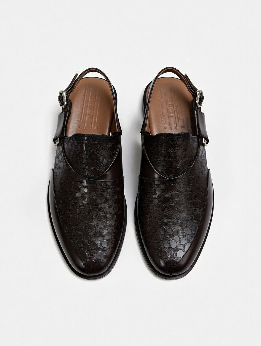Pair of black leather shoes with strap details on a white background