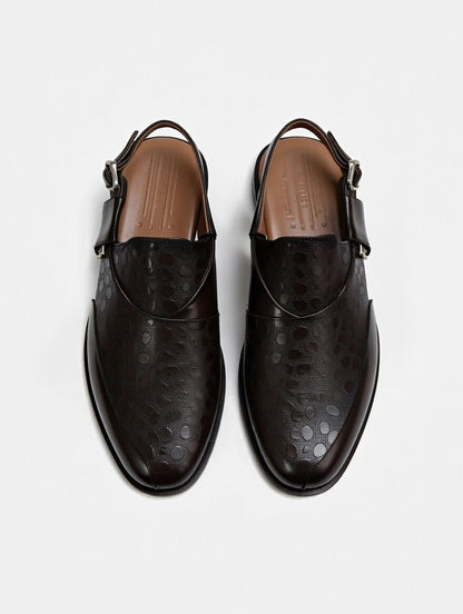 Pair of black leather shoes with strap details on a white background