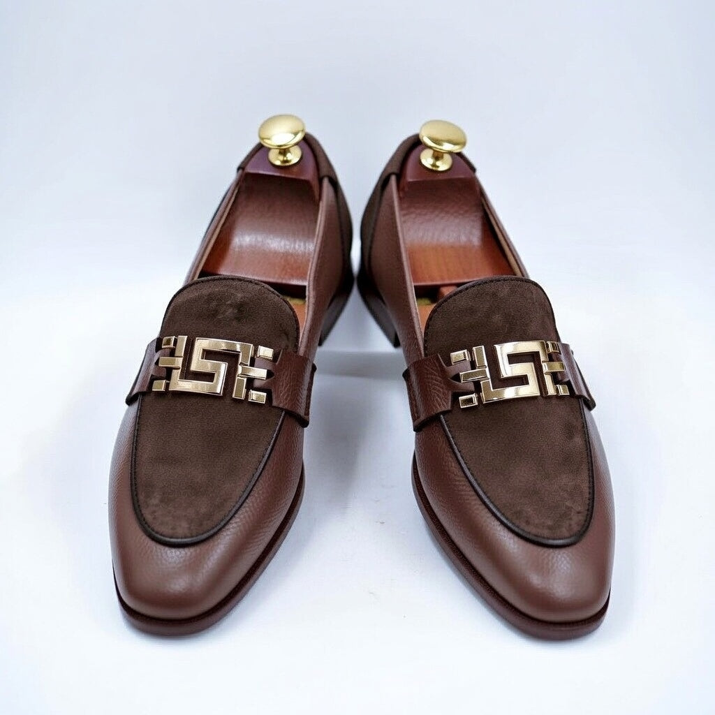 Pair of brown loafers with gold accents on a white background