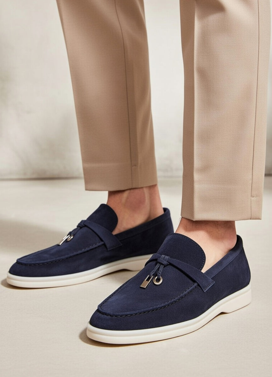 Navy loafers worn with beige pants on a neutral background