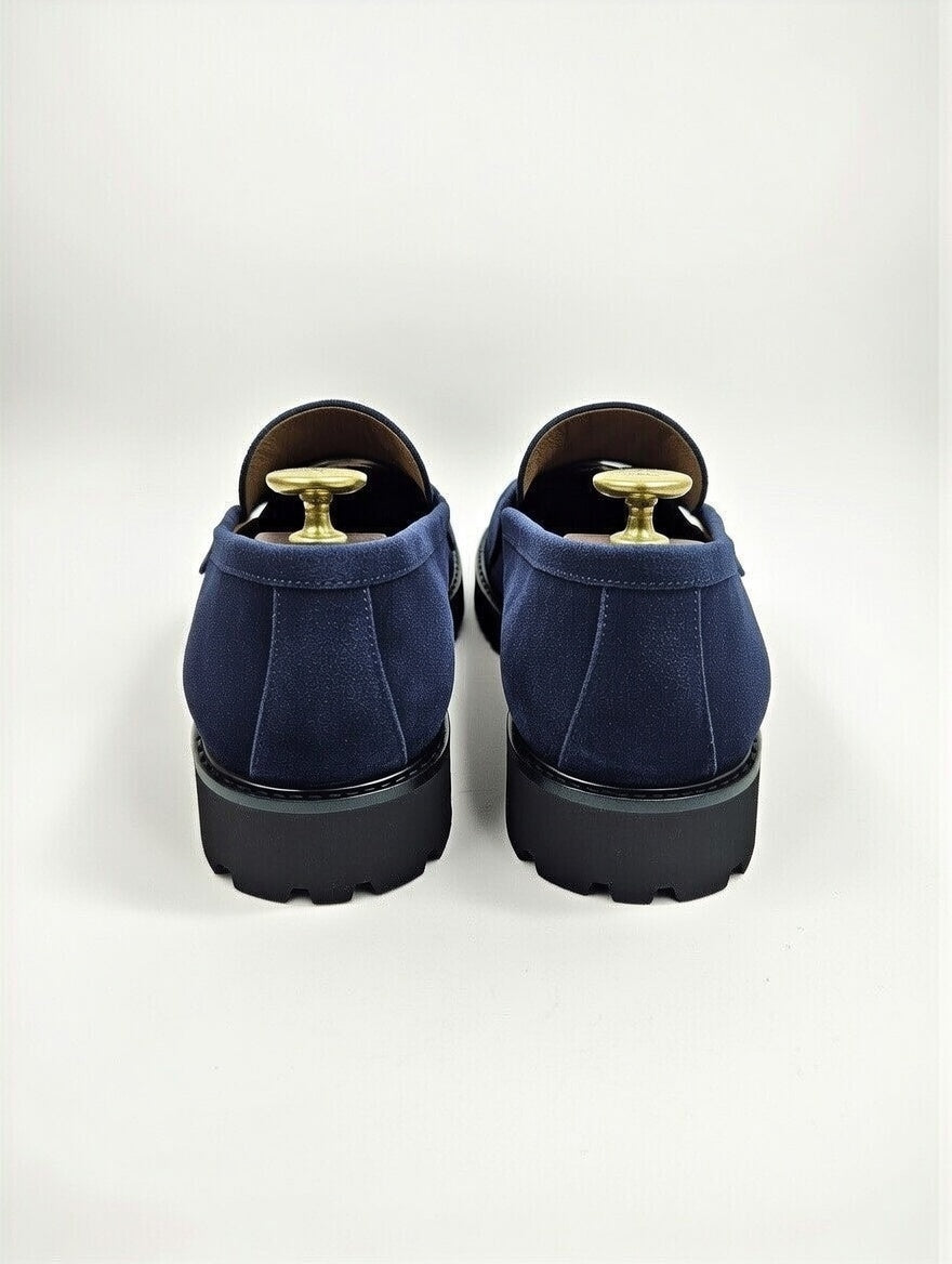 Pair of blue loafers with gold accents on a light gray background