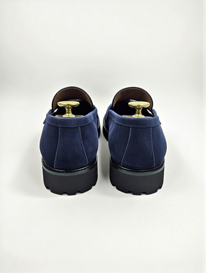 Pair of blue loafers with gold accents on a light gray background