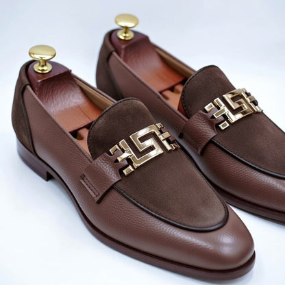 Brown leather loafers with gold accents on a white background